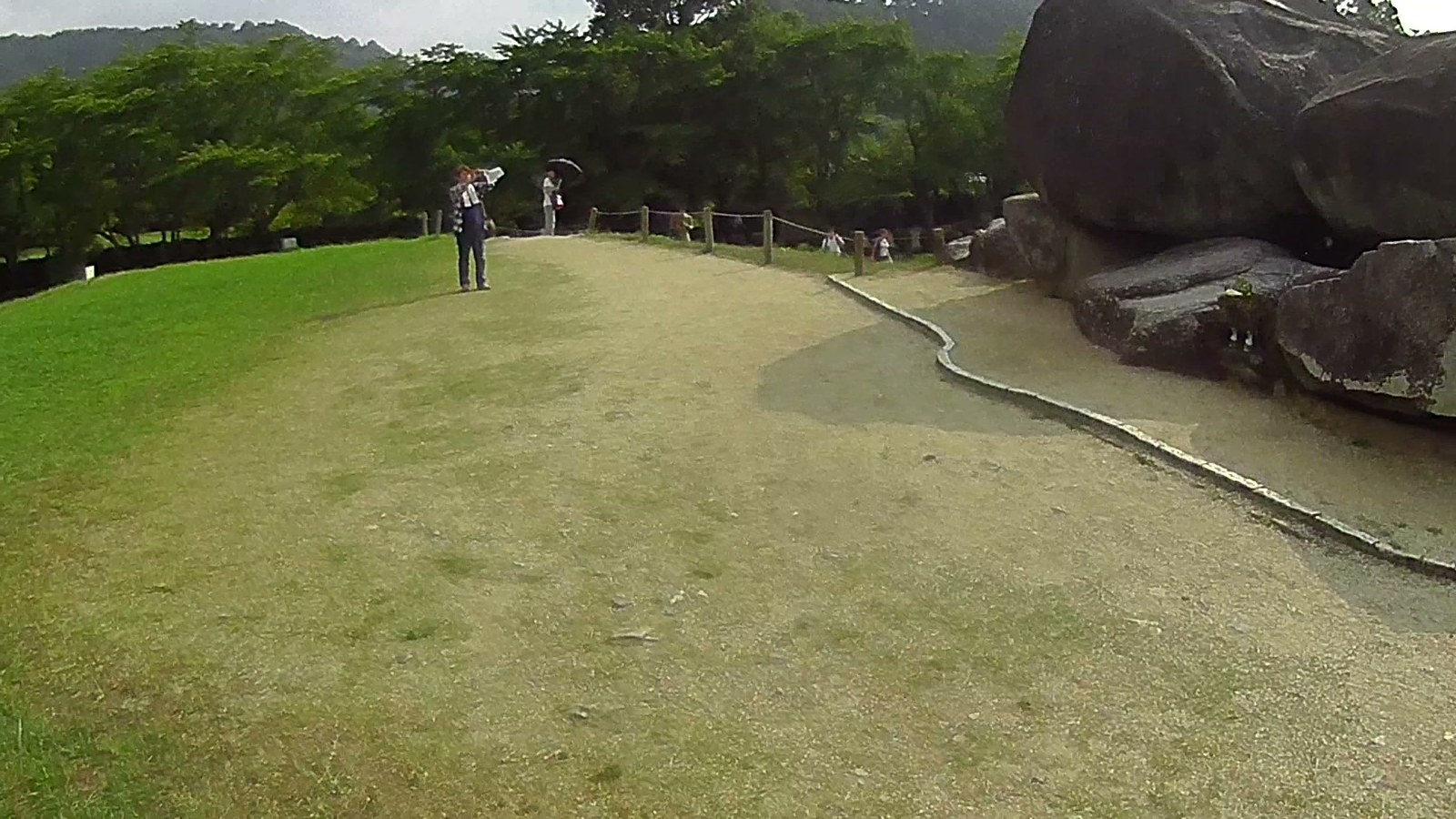 石舞台古墳を遠くから。手前の芝生と、写真を撮る人