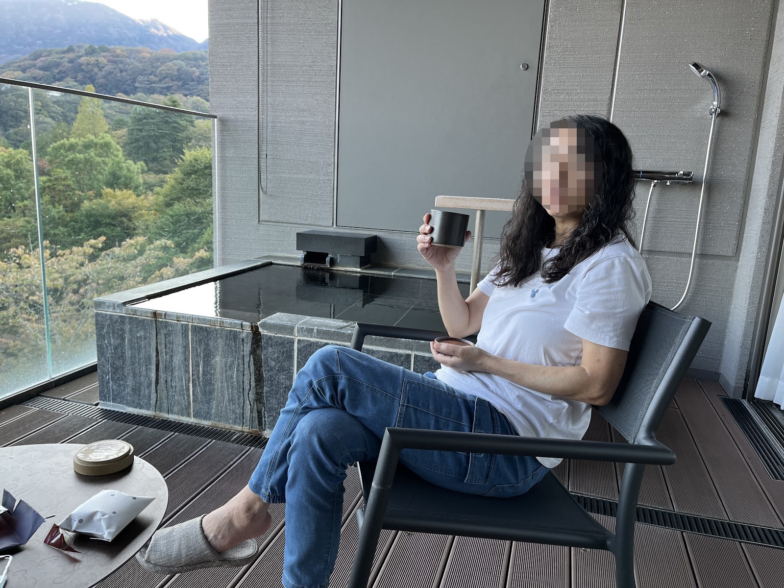 客室テラスの椅子でお茶を飲む。背後に露天風呂と紅葉の谷