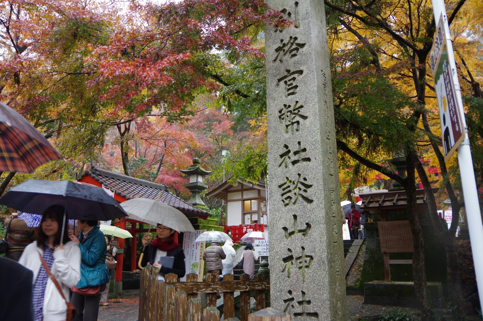 「別格官幣社 談山神社」と刻まれた社号標と、傘をさした参拝者