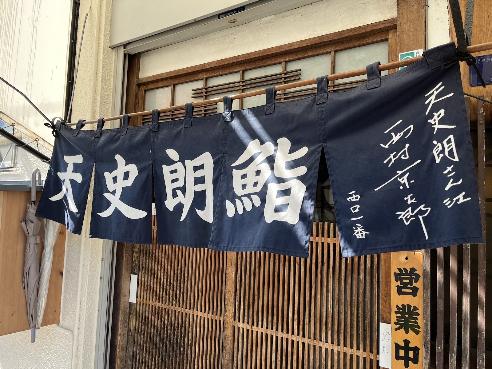 小田原の天史朗鮨の紺色の暖簾と営業中の札
