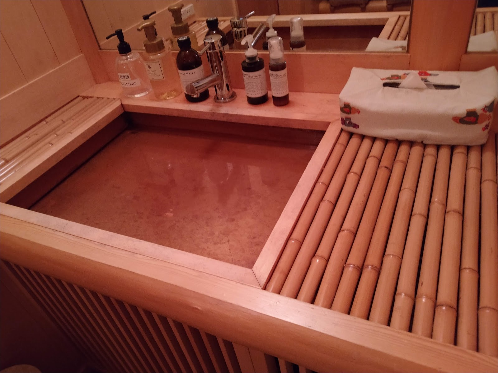 月日亭の浴槽のふちに並んだアメニティと、すのこ