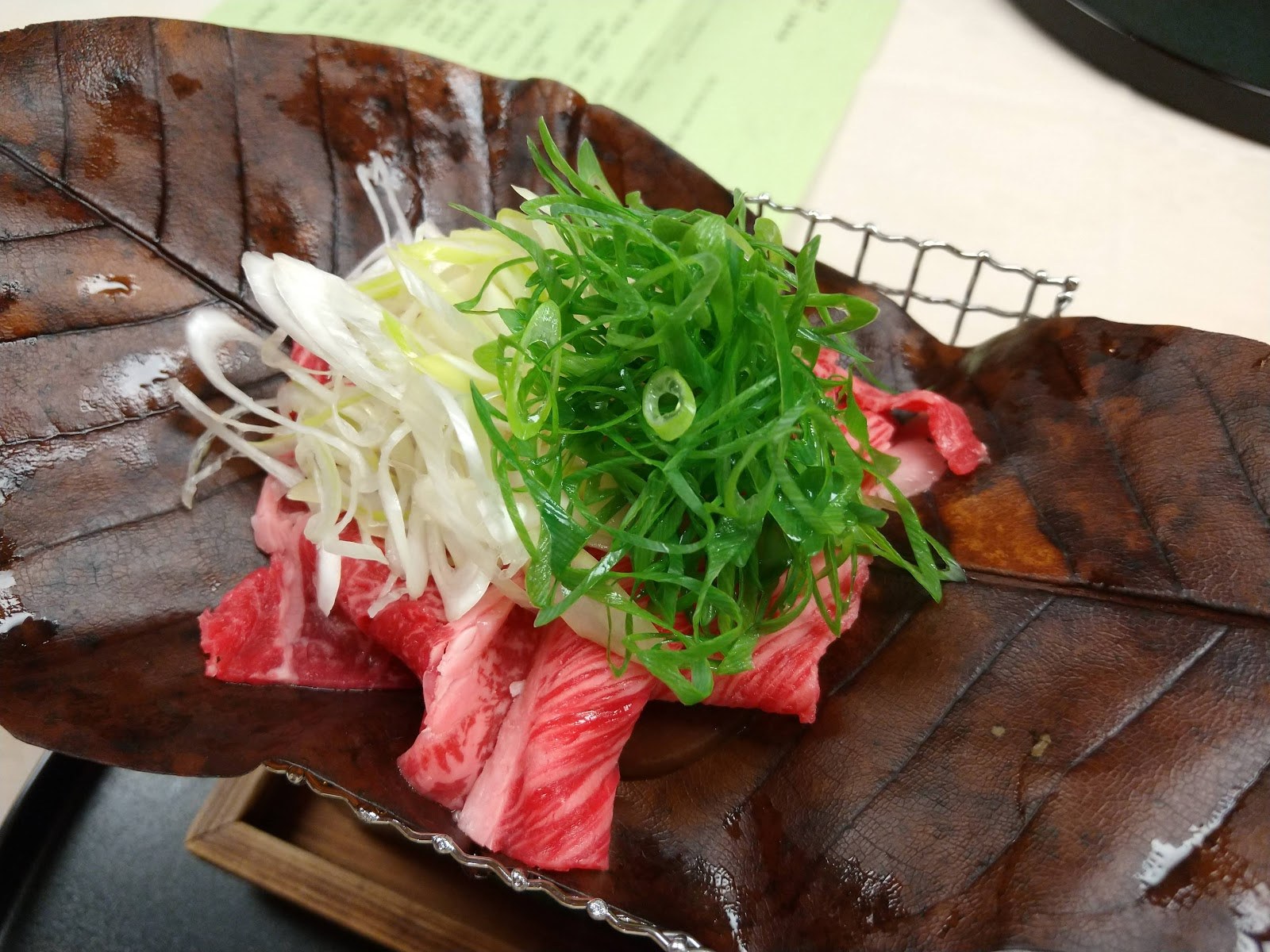 朴葉の上に載せた大和牛と九条ねぎ。下に火が入っている